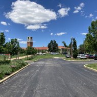 The Visitor Center is in the background under a blue sky with paved parking lot in the foreground