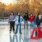 Ice skaters move on Steinberg Rink, with their legs reflecting off the ice.
