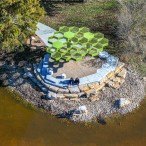 Green, honeycombed screened roof above a circular spot to sit or stand next to the water