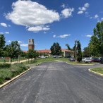 The Visitor Center is in the background under a blue sky with paved parking lot in the foreground